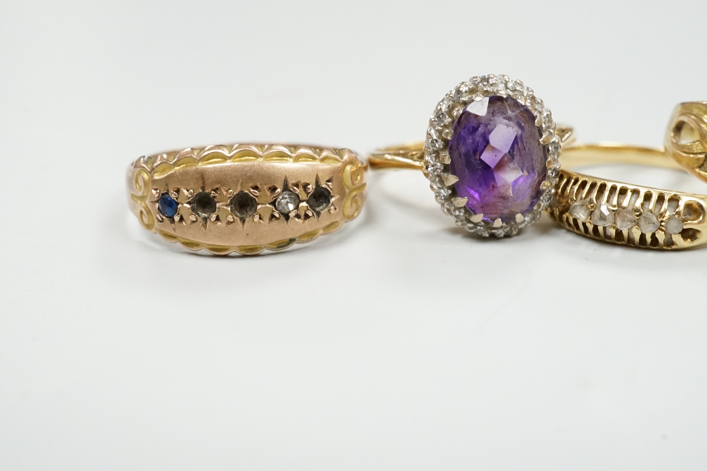 An 18ct, amethyst and diamond set oval cluster ring, size K and four other rings including gem set.